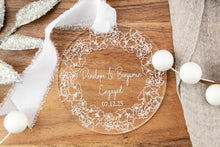 Load image into Gallery viewer, Clear acrylic round engagement ornament on engraved with names and engagement date with thick floral wreath. Displayed on a wooden tray.
