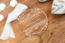 Load image into Gallery viewer, Clear Acrylic Round Personalized Anniversary Ornament with Couple's Names and wedding Year strung on a white ribbon displayed on a wood tray with decorative elements.