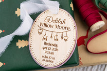 Load image into Gallery viewer, Personalized wooden baby birth stats ornament with pink acrylic backing displayed on green Christmas wrapping paper.