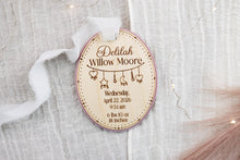 Load image into Gallery viewer, Full view of a personalized oval baby birth announcement ornament with engraved name, birth statistics, and pink backing.