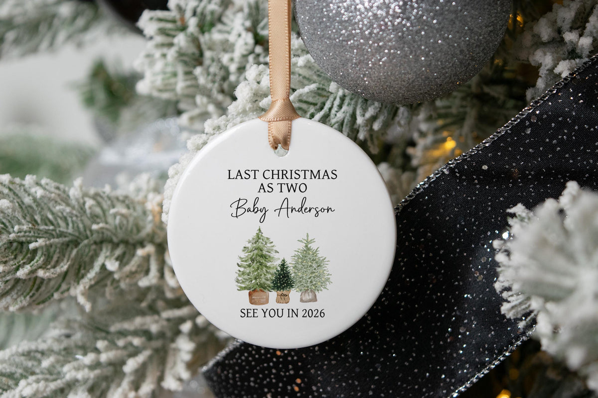 Last Christmas as Two Ornament with the baby's last name and three christmas trees with see you in the year the baby is due hanging on a white christmas tree.