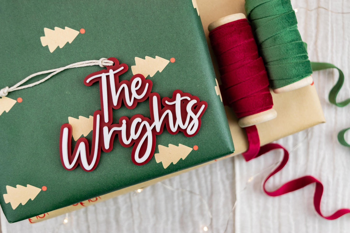 Personalized family name Christmas ornament reading The Wrights, with layered white acrylic lettering on a red backer.
