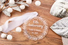 Load image into Gallery viewer, Clear Acrylic 10th Anniversary Ornament, personalized with your names and wedding year with decorative elements on a wooden surface
