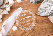 Load image into Gallery viewer, Clear Acrylic 10th Anniversary Ornament, personalized with your names and wedding year with decorative elements on a wooden surface
