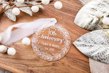Load image into Gallery viewer, Clear Acrylic 10th Anniversary Ornament, personalized with your names and wedding year with decorative elements on a wooden surface

