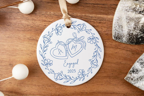 Decorative ornament with blue design on a wooden surface with white berries and silver leaves.
