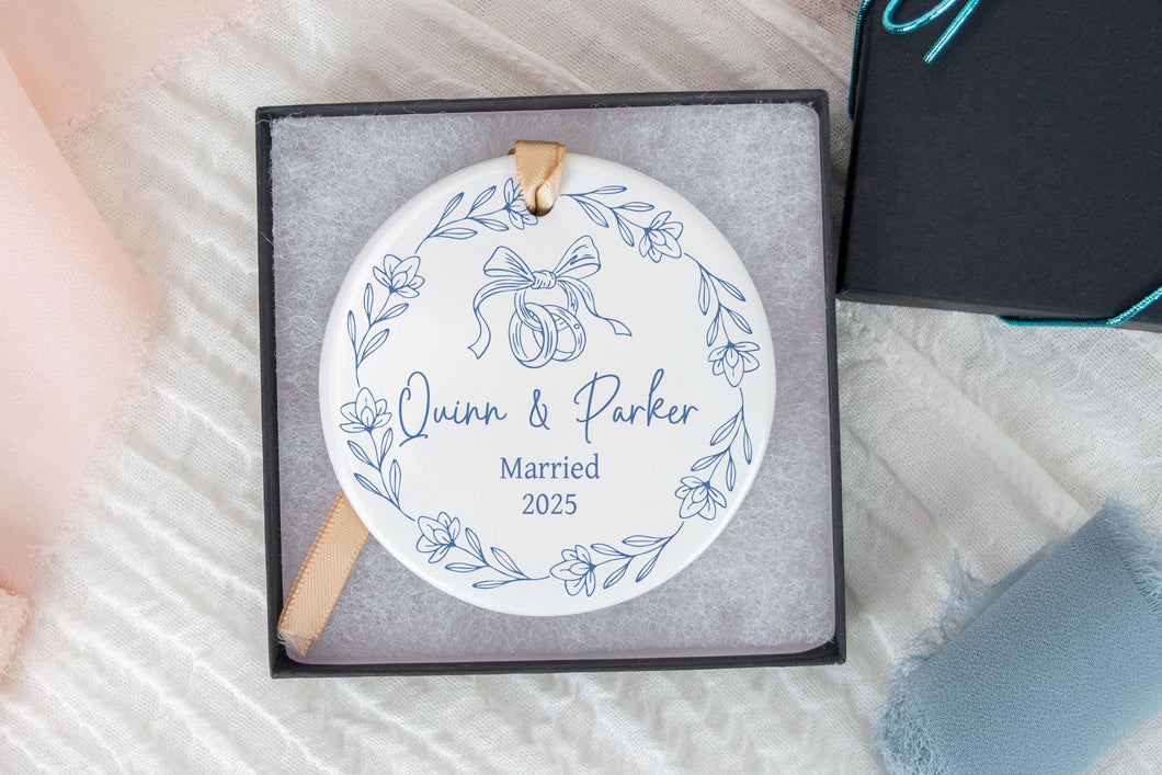 Blue Toile Christmas Ornament with 'Names Married 2025' text in a box on a textured surface.