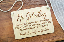 Load image into Gallery viewer, Front view of a rectangular wooden No Soliciting sign with engraved lettering and white cotton rope hanger.
