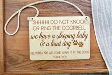 Load image into Gallery viewer, Rectangular birch wood door sign with cotton rope hanger, engraved sleeping baby and loud dog message, and paw prints.
