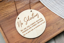 Load image into Gallery viewer, Angled view of a round birch wood No Soliciting sign with brown suede cord and engraved lettering.
