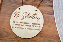 Load image into Gallery viewer, Round wooden No Soliciting sign with engraved lettering and brown suede cord hanger, shown on a wooden tray.
