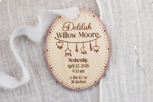 Load image into Gallery viewer, Oval wood baby birth stats ornament with pink acrylic backing, engraved with Delilah Willow Moore, birth details, and hanging charms.
