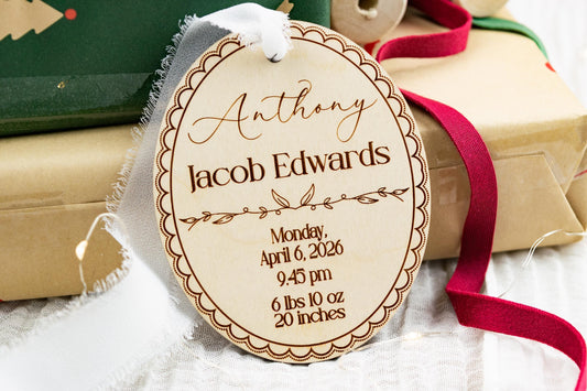 Oval wooden baby birth stats ornament engraved with Anthony Jacob Edwards, birth details, scalloped border, and floral vine design.