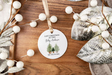 Load image into Gallery viewer, Personalized Christmas ornament made from white ceramic that says last Christmas as two with the baby's last name with two big trees and one little tree. the bottom says see you in the year the baby is to be born. The ornament is displayed on a wooden tray.
