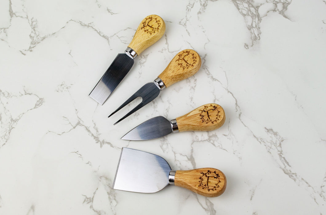 cheese knives with letter f and wreath detail on a cutting board